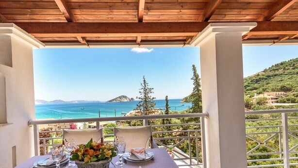 Une table dressée pour le dîner, avec vue sur la mer et les collines.