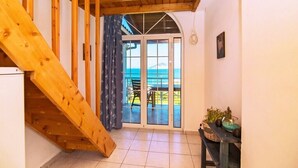 Un escalier en bois menant à un balcon d’où l’on peut admirer la mer.