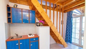 Une cuisine avec des meubles bleus, un réfrigérateur blanc et un escalier en bois.