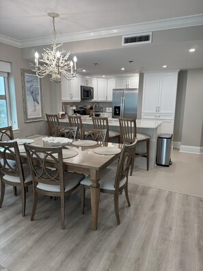 A modern kitchen with white cabinets, stainless steel appliances, and a chandelier. - MVG 1213 Oceanfront, corner, southern side (North Myrtle Beach)