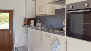 Una cucina moderna con mobili bianchi, forno integrato e piano cottura a gas.