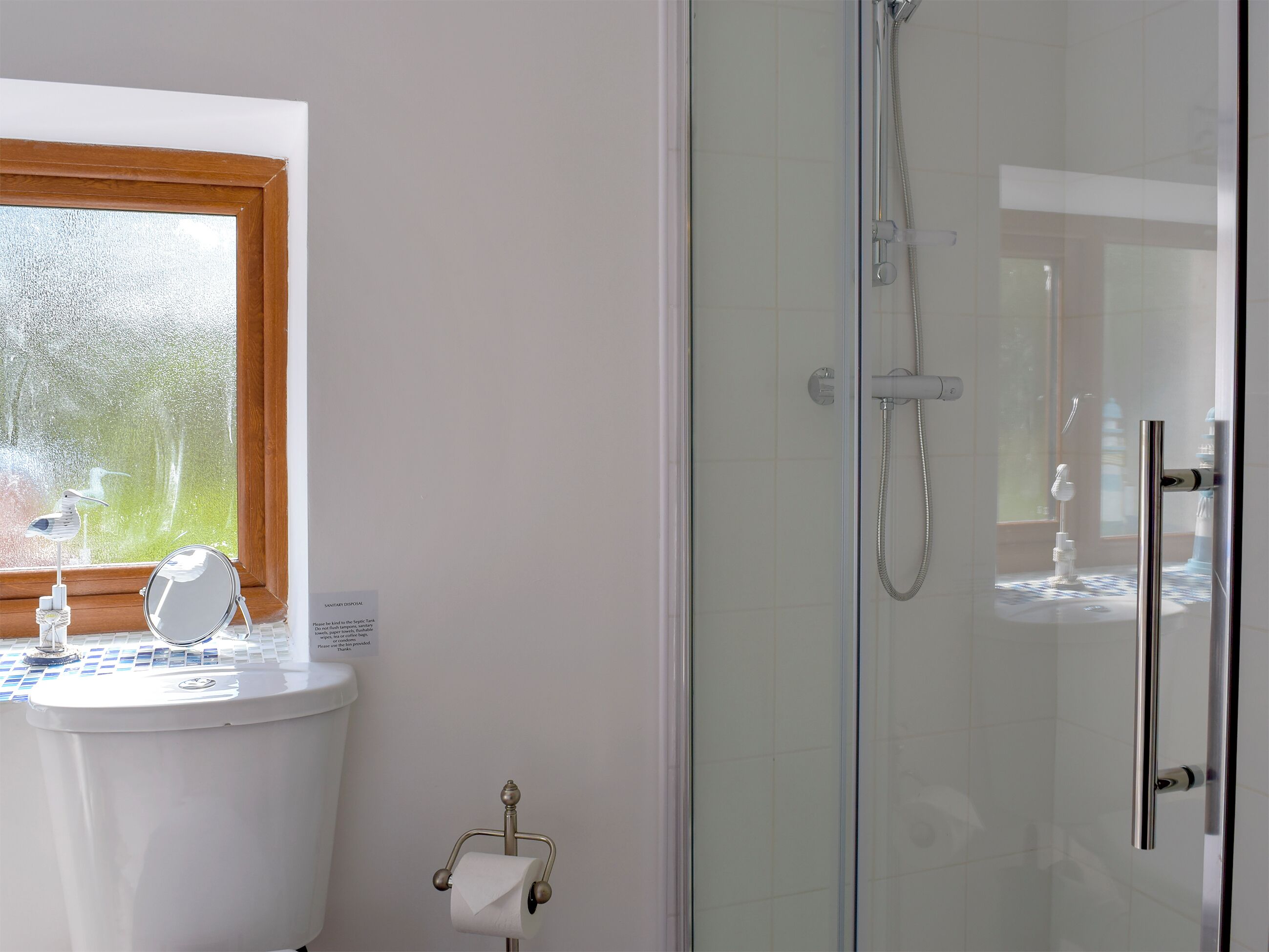 Een badkamer met toilet, een douchecabine en een raam.