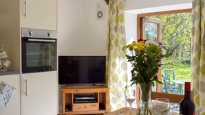 Una cucina con TV, tavolo in legno e finestra vista su spazi verdi.
