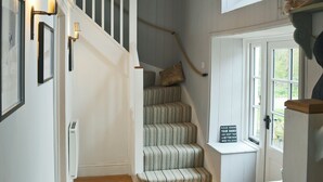 Eine Treppe mit Streifenmuster, eine weiße Tür mit einem Schild und ein Fenster mit Blick auf Grünflächen.