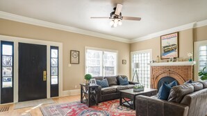 A living room with a brown leather sofa, a coffee table, and a fireplace. There are two doors, a window, and a ceiling fan. - The most beautiful home in Historic East Side of Kalispell. @whitehouse_project  (Kalispell)