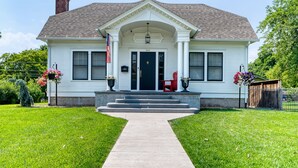 A two-story house with a front porch, a flag, and steps leading to the door.