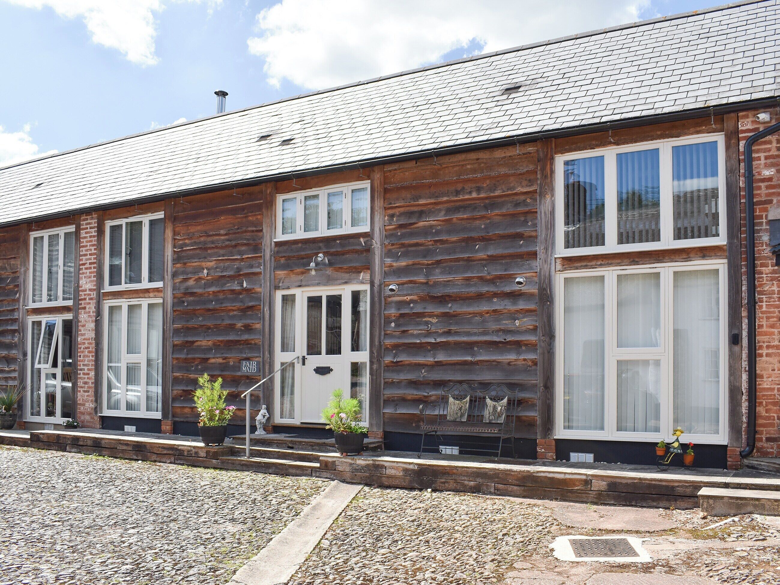 Un bâtiment de style « chalet en rondins », avec une façade en briques, de grandes fenêtres et une allée gravillonnée.