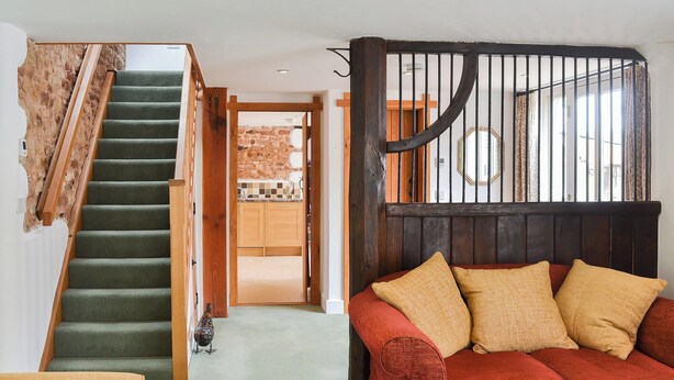 A staircase leading to a kitchen area with wooden cabinets and a window with curtains. - 2 bedroom accommodation in Kentisbeare, Cullompton (Kentisbeare, Cullompton)