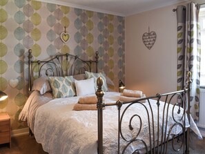 A neatly made bed with a patterned wall and a heart-shaped decoration.