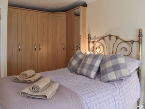 A bedroom with a bed, pillows, a headboard, and a wardrobe.