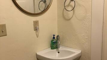 A bathroom with a white sink, a round mirror, and two wall-mounted towel rings.