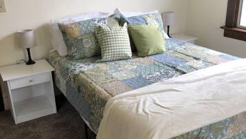 A bedroom with a bed, two bedside tables, and a window.