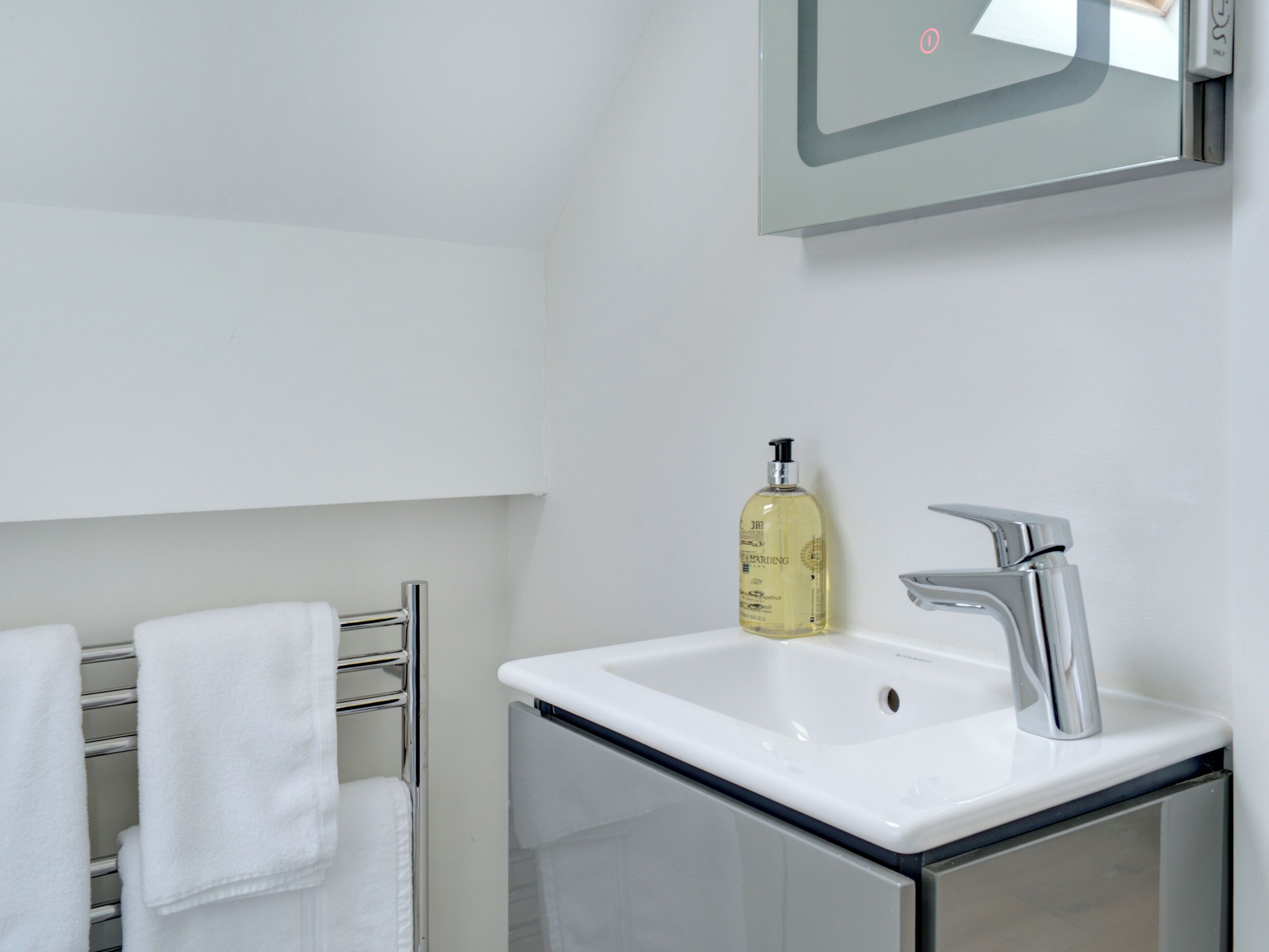 Une salle de bain avec un lavabo blanc, un robinet chromé et un flacon de savon pour les mains.
