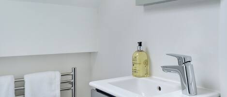 Une salle de bain avec un lavabo blanc, un robinet chromé et un flacon de savon pour les mains.