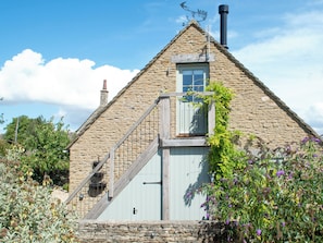 Une maison en pierre avec un escalier en bois menant à un balcon.