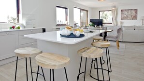 Eine moderne Küche mit einer zentralen Kochinsel, Barhocker und Pendelleuchten.