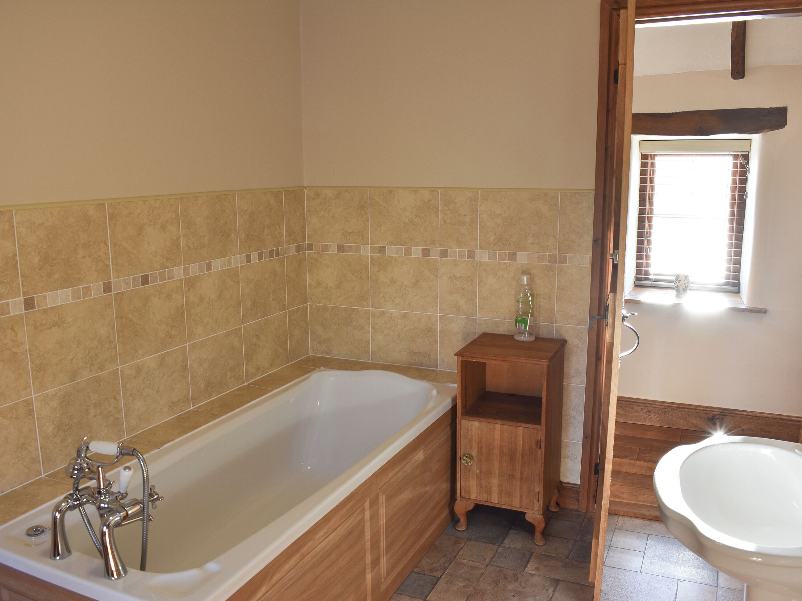 Une salle de bain avec une baignoire, un meuble en bois et des toilettes.