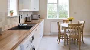 A modern kitchen with white cabinets, a sink, a toaster, and a window with a view of greenery.