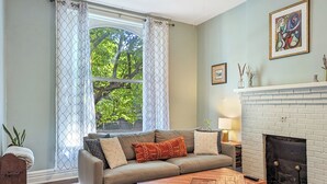 A living room with a sofa, coffee table, fireplace, and a window with curtains.