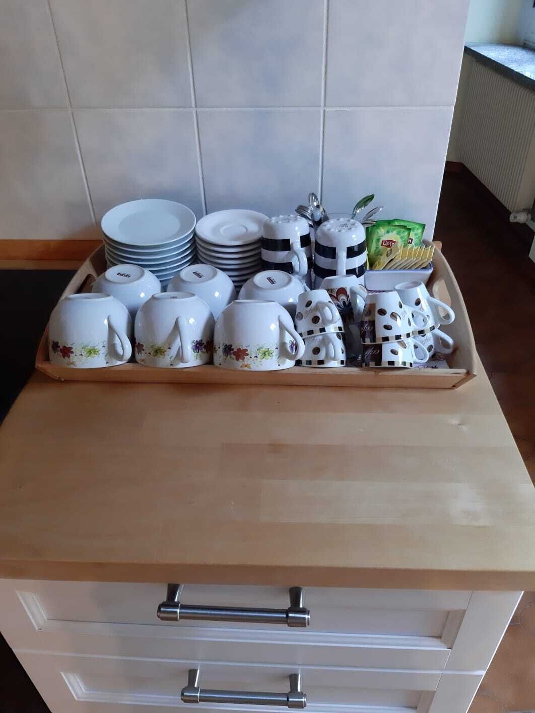 A kitchen counter with a tray of white ceramic cups, plates, and a teapot.