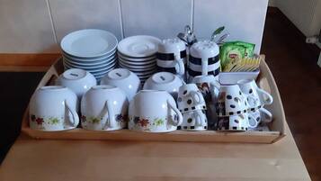 A kitchen counter with a tray of white ceramic cups, plates, and a teapot.