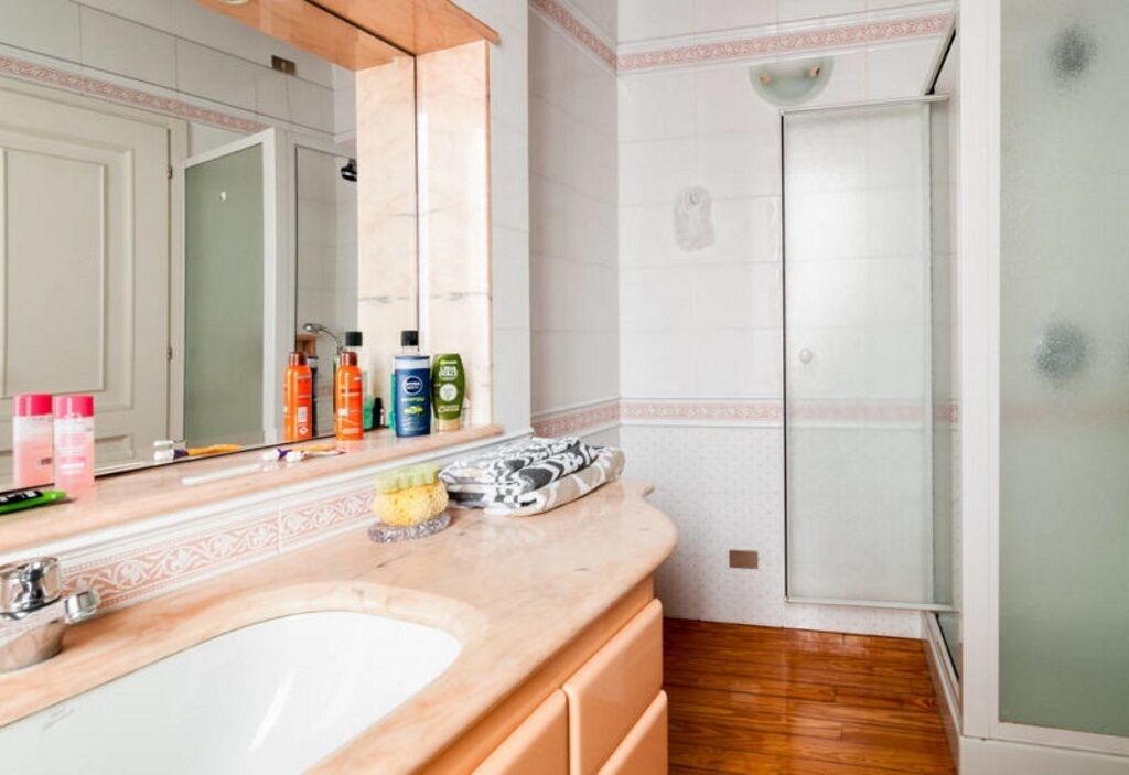 Ein Badezimmer mit großem Spiegel, Waschbecken und Dusche.