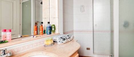 Une salle de bain avec un grand miroir, un lavabo et une douche.
