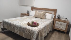 Cama bem arrumada com um edredom estampado, cabeceira de madeira e duas mesas de cabeceira com gavetas.