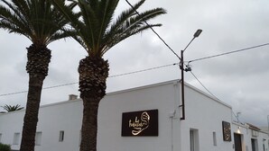 Um edifício com base de pedra e paredes brancas, exibindo uma placa com um coração e a palavra 'habitable'.