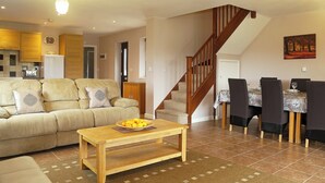 Un salon comprenant un canapé, une table basse, une table à manger avec des chaises et un escalier.