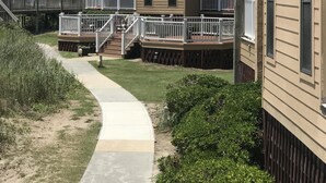 A multi-story residential building with balconies, a covered walkway, and a landscaped area. - Enjoy an oceanfront getaway with beautiful beach steps from your door.   (North Topsail Beach)