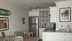 A modern kitchen with white cabinets, a stainless steel refrigerator, and a ceiling fan. - Enjoy an oceanfront getaway with beautiful beach steps from your door.   (North Topsail Beach)