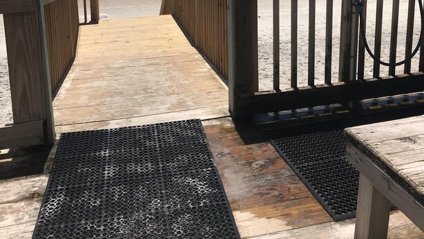 A wooden boardwalk leading to a beach with a metal railing and a lamp post. - Enjoy an oceanfront getaway with beautiful beach steps from your door.   (North Topsail Beach)