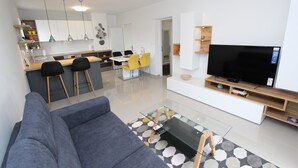 A modern living room with a gray sofa, a glass coffee table, and a TV on a wooden stand. - SORRISO 2 Two-Bedroom Apartment (Rovinj)
