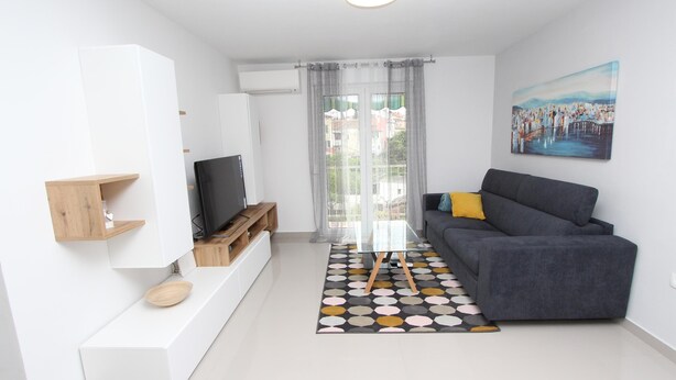 A modern living room with a grey sofa, a glass coffee table, and a painting on the wall. - SORRISO 2 Two-Bedroom Apartment (Rovinj)