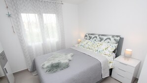 A bedroom with a bed, a nightstand, a lamp, and a window with curtains. - SORRISO 2 Two-Bedroom Apartment (Rovinj)