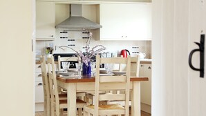 A kitchen with white cabinets, a wooden dining table, and chairs.