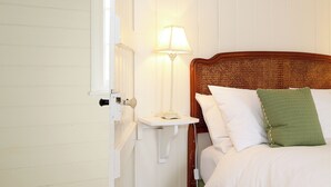 A bedroom with a wooden headboard, a bedside table with a lamp, and a bed with pillows.