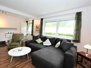 A modern living room with a grey sofa, a green armchair, and a white coffee table. - Nice apartment for 6 guests with WIFI, TV, terrace and panoramic view (Hippach)