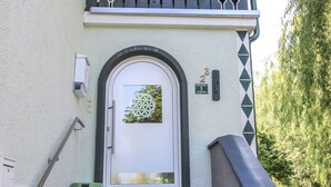A building entrance with a white door, a small window with a geometric design, and a staircase leading up. - Beautiful apartment for 6 people with WIFI, TV, terrace and panoramic view (Hippach)