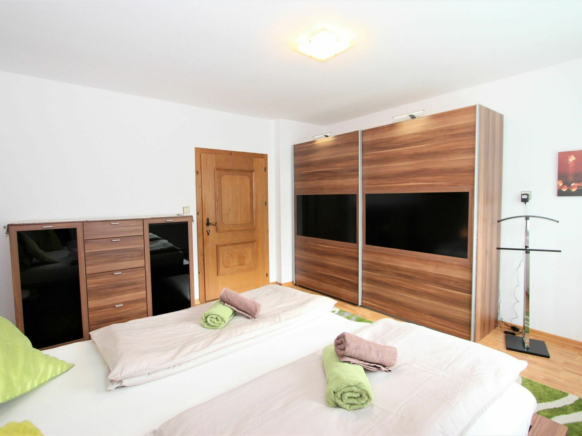Un dormitorio con cama, armario, puerta y lámpara de pie.
