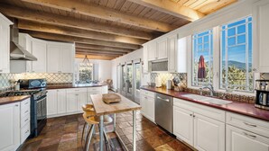 A kitchen with white cabinets, a wooden ceiling, and a large window with a view of mountains. - Heavenly Mountain Views-Close to Plaza, Hot tub, Ski & Pickleball, Upscale home (Santa Fe)