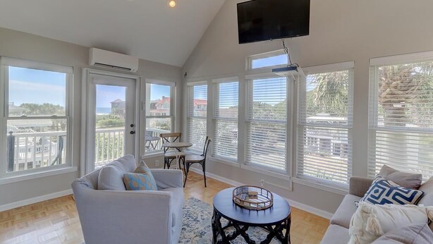 Un salón espacioso con ventanas amplias, un televisor de pantalla plana y un balcón con vistas.