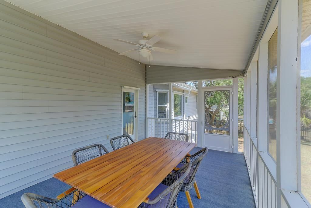 A covered porch with a wooden table and chairs, a ceiling fan, and a view of the backyard.