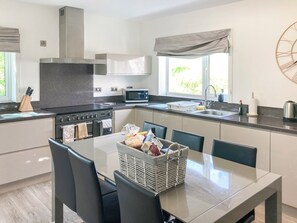 A modern kitchen with a dining area, stainless steel appliances, and a large window.