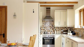 Una cocina compacta con zona de comedor, que incluye una mesa de madera, sillas, horno empotrado y lavadora.