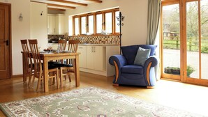 Amplia sala de estar con mesa de comedor, sillas, un sillón azul y un ventanal con vistas al exterior.
