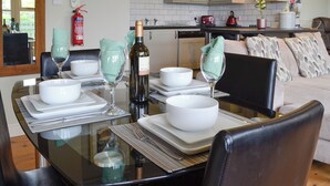 Un tavolo da pranzo apparecchiato con ciotole bianche, tovaglioli verdi e bicchieri da vino. Sulla tavola c'è una bottiglia di vino.