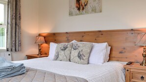 Un letto rifatto con cura, con una coperta a motivi decorativi, una testiera in legno e un quadro raffigurante un toro sulla parete.