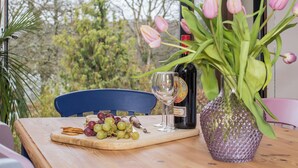 Ein Tisch mit einer Weinflasche, einem Glas, einer Vase mit rosa Tulpen und einem Schneidebrett mit Trauben und Crackern.